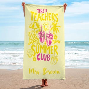 May include: A pale yellow beach towel with the text "Tired Teachers Summer Club" in yellow and pink. The towel design includes illustrations of a beach umbrella, sunglasses, a beach chair, drinks, a seashell, flowers, and flip-flops. The name "Mrs. Brown" is printed.