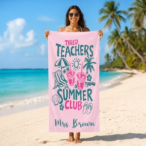 May include: A pink beach towel with the words "Tired Teachers Summer Club" in teal and pink. The towel features illustrations of a beach umbrella, sunglasses, a beach chair, drinks, a seashell, a flower, and flip-flops. The name "Mrs. Brown" is printed at the bottom.