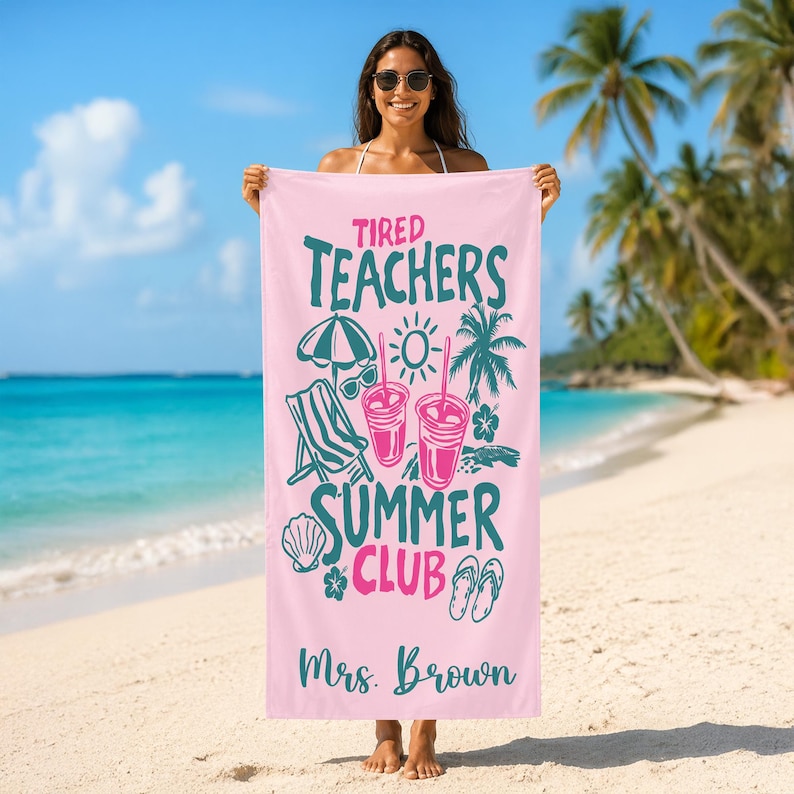 May include: A pink beach towel with the words "Tired Teachers Summer Club" in teal and pink. The towel features illustrations of a beach umbrella, sunglasses, a beach chair, drinks, a seashell, a flower, and flip-flops. The name "Mrs. Brown" is printed at the bottom.