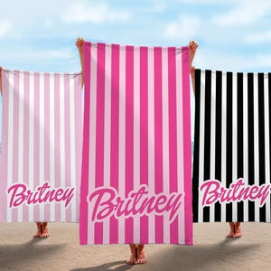 May include: Three beach towels with pink and white stripes, black and white stripes, and pink and white stripes. Each towel has the name "Britney" written in pink on it.