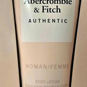 Może przedstawiać: Beżowa tubka balsamu do ciała z logo Abercrombie & Fitch i czarnym napisem "AUTHENTIC". Etykieta zawiera r&oacute;wnież napisy "WOMAN/FEMME" i "BODY LOTION EMULSION POUR LE CORPS 200 ml e."