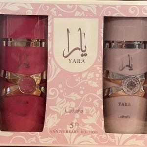 Peut inclure: Coffret cadeau de parfum avec deux flacons. L'un est rose fonc&eacute;, l'autre rose clair, tous deux avec des d&eacute;tails dor&eacute;s et argent&eacute;s. Les flacons portent l'inscription arabe "Yara". La bo&icirc;te rose porte l'inscription "5th Anniversary Edition".