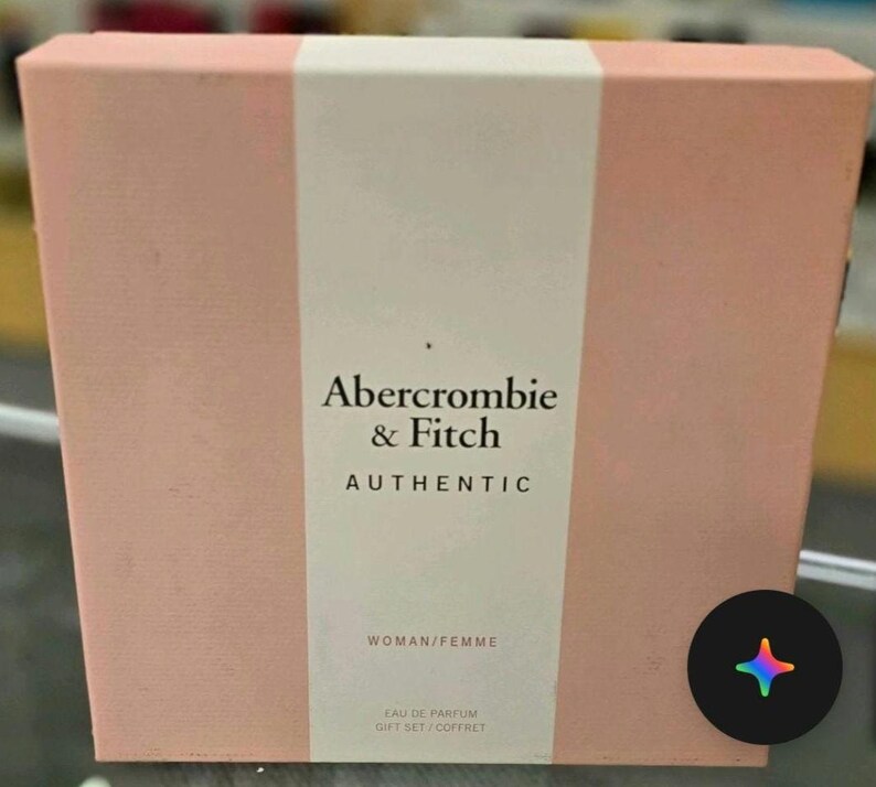 Może przedstawiać: Prostokątne r&oacute;żowe pudełko prezentowe z białym pionowym paskiem. Zawiera tekst "Abercrombie & Fitch AUTHENTIC" i "WOMAN/FEMME". Na dole pudełka widnieje napis "EAU DE PARFUM GIFT SET/COFFRET".