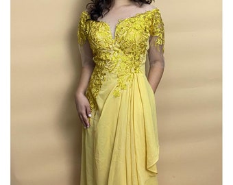 May include: A yellow maxi dress with a V-neckline and short sleeves. The dress has intricate floral embroidery and a flowing skirt. The dress is made of a soft, lightweight fabric.
