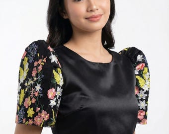 May include: Black satin top with floral embroidered sleeves. The sleeves feature a colorful array of pink, yellow, and white flowers. The text "VARIETYKART BY MRS" is visible on the front of the top.