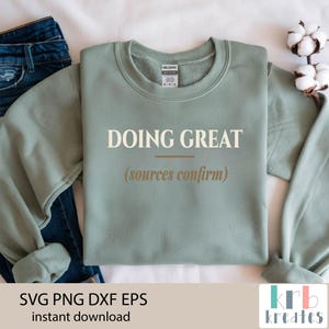 Op de afbeelding: Een saliegroene sweatshirt met de woorden "DOING GREAT" in een schreefletter, met "(sources confirm)" eronder. De sweatshirt is opgevouwen naast een spijkerbroek en een takje katoen. De onderkant van de afbeelding bevat de tekst "SVG PNG DXF EPS instant download".
