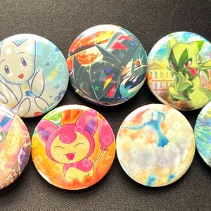 May include: A collection of colorful round buttons featuring various cartoon characters. The buttons display a variety of designs, including a white and blue creature, a pink and orange character, and a black and yellow character.