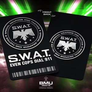 以下が含まれることがあります： SWATのロゴと「S.W.A.T. EVEN COPS DIAL 911」というテキストが刻まれた、黒と銀のレーザー彫刻金属カード。