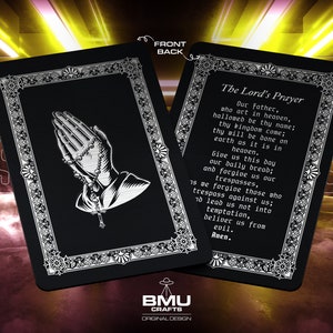 May include: Black card with silver trim featuring a prayer card with the Lord's Prayer printed in white text. The back of the card has a silver image of praying hands holding a rosary.