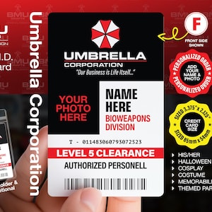 May include: A black and white Umbrella Corporation prop ID card. The card features the Umbrella Corporation logo, the text "Your Photo Here", "Name Here", and "Level 5 Clearance". The card is sized 85mm x 54mm.