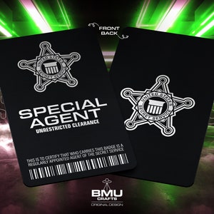 May include: A black and white special agent badge with the text "United States Secret Service" and "Special Agent" with the words "Unrestricted Clearance" below. The badge is on a black background with a barcode and the text "This is to certify that who carries this badge is a regularly appointed agent of the Secret Service".