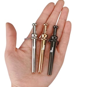 May include: Three metal tools in silver, gold, and black, each with a small chain. The tools have a cylindrical body and a rounded top. The text "TEE BUMPS" is printed on the gold and black tools.