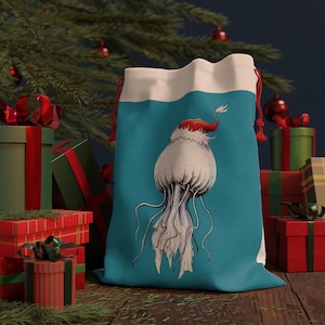 Può includere: Un sacco regalo turchese con coulisse raffigurante una medusa con un cappello da Babbo Natale. La medusa è bianca con tentacoli grigi. La borsa ha una parte superiore bianca e un cordoncino rosso. I regali e un albero di Natale sono sullo sfondo.