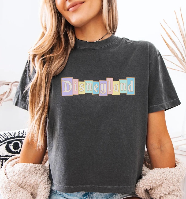 A woman wearing a black t-shirt with the word "Disneyland" printed on it.