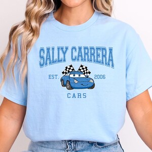 a woman wearing a blue t - shirt with a car on it