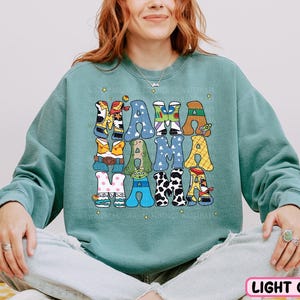 a woman sitting on a bed wearing a green sweatshirt