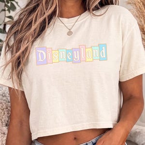 A woman wearing a white t-shirt with the word "Disneyland" printed on it.
