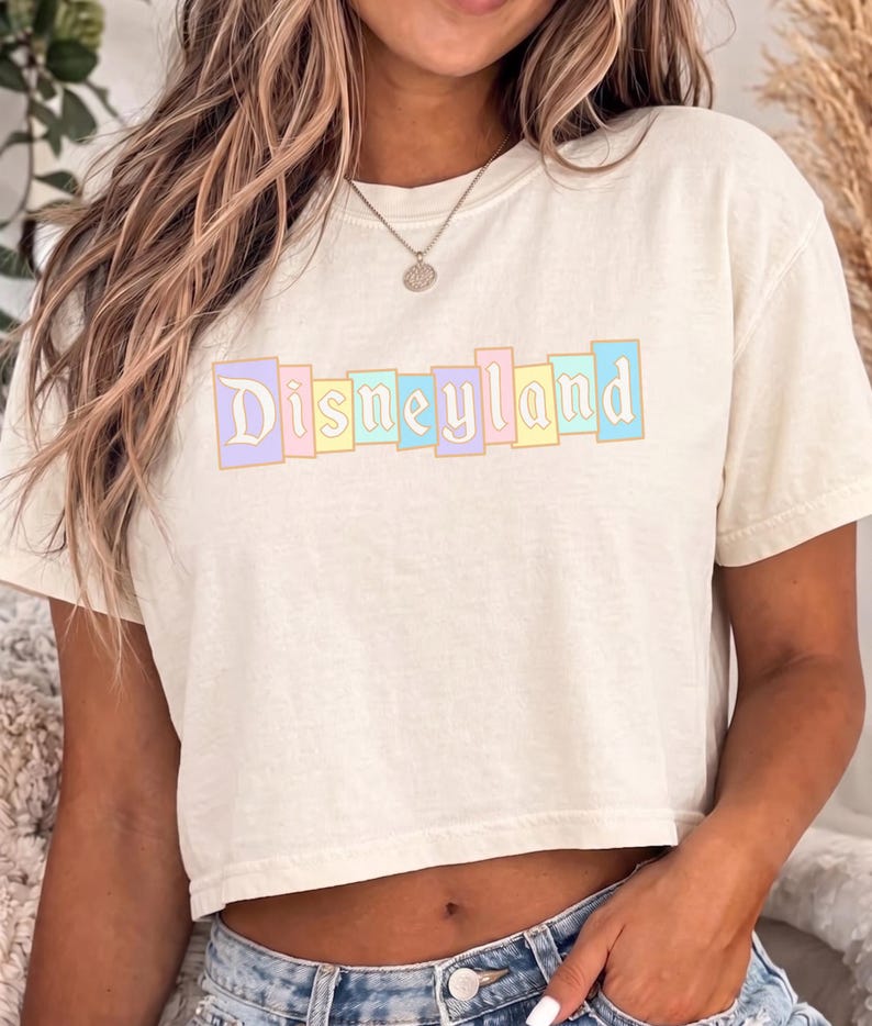 A woman wearing a white t-shirt with the word "Disneyland" printed on it.