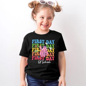 a little girl wearing a t - shirt that says first day first day first day