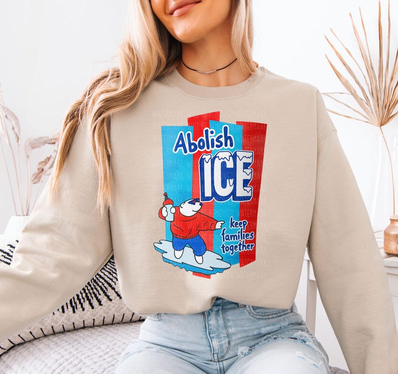a woman sitting on a bed wearing a sweatshirt