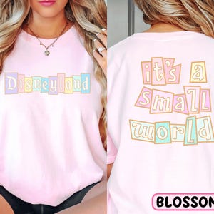 A woman wearing a pink t-shirt with the text "Disneyland it's a small world" printed on it.