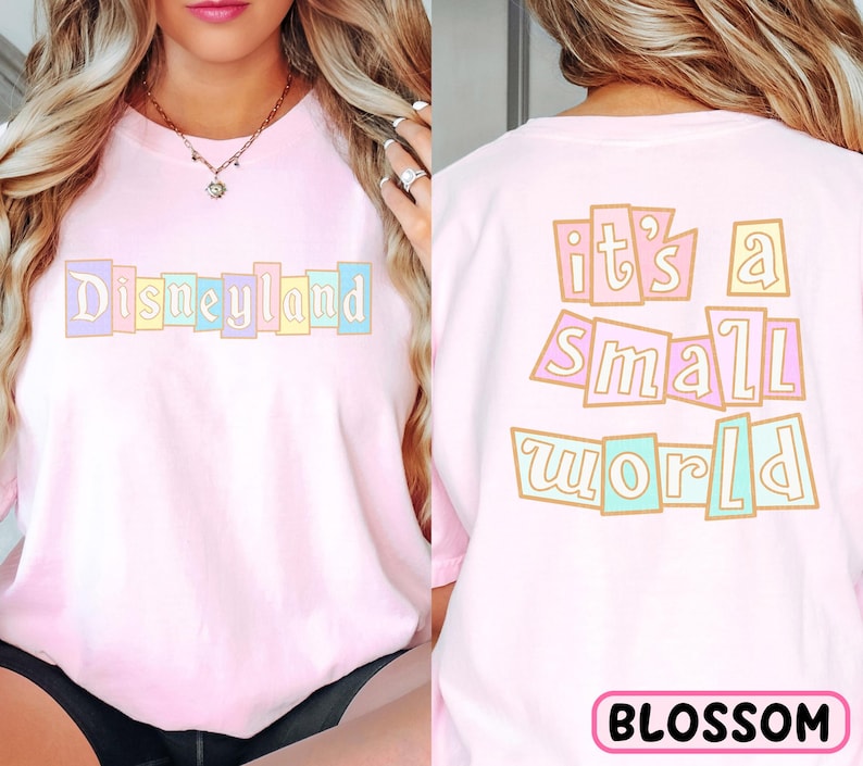 A woman wearing a pink t-shirt with the text "Disneyland it's a small world" printed on it.