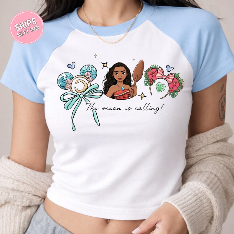 A woman wearing a white and blue t-shirt with a graphic design featuring a cartoon character and text.
