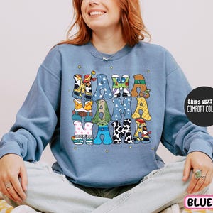 a woman sitting on a bed wearing a blue sweatshirt