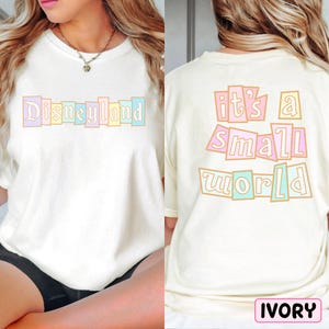A white t-shirt with the text "Disneyland it's a small world" printed on it, along with a necklace.