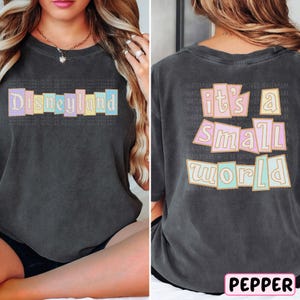A woman wearing a black t-shirt with the text "Disneyland it's a small world" printed on it.