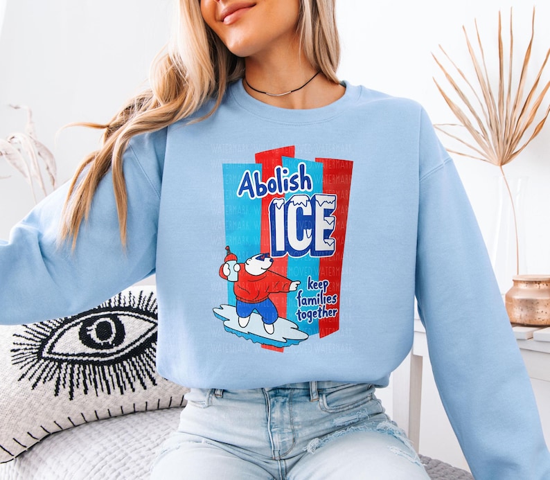a woman sitting on a bed wearing a blue sweatshirt