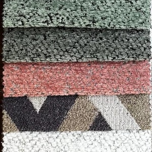 May include: A vertical display of various textured fabric swatches. The samples showcase a range of colors, including gray, white, brown, and blue. Some swatches feature geometric patterns, while others have a solid, plush appearance. Ideal for home decor.
