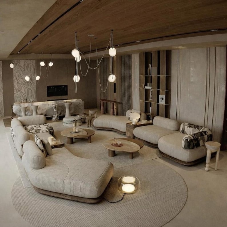May include: A modern living room with a neutral color palette. The room features curved sofas, wooden coffee tables, and a round rug. Overhead, globe pendant lights hang from the ceiling. The space is designed with a focus on natural materials and a minimalist aesthetic.