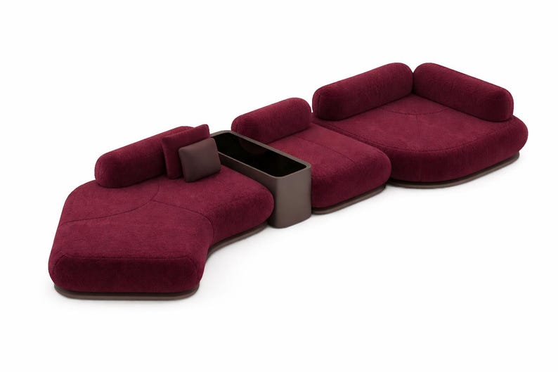 May include: Modular burgundy sofa set with rounded shapes. The set includes multiple seating sections, cylindrical backrests, and a built-in dark brown storage unit. The sofa is upholstered in a textured fabric.