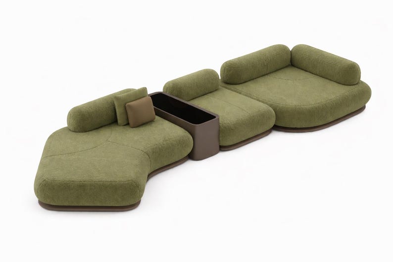 May include: A modular olive green sofa with rounded sections and a built-in dark brown storage unit. The sofa includes two cylindrical bolster pillows and two square pillows. The base of the sofa is a dark brown color.