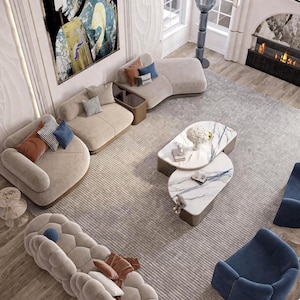 May include: An overhead view of a modern living room with beige curved sofas, blue armchairs, and a patterned rug. Two marble-topped coffee tables are in the center, and decorative pillows add color. A fireplace and artwork complete the stylish interior.