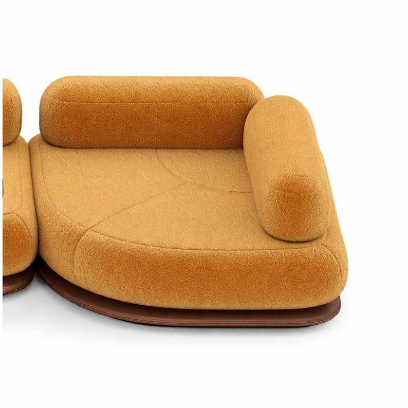 May include: A modern, modular sofa in a warm mustard yellow color. The sofa features rounded edges and a soft, textured fabric. The base is a dark brown, curved shape. The design is contemporary and inviting.