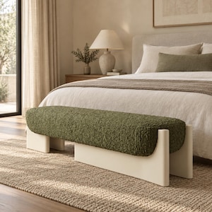 May include: A rectangular bench featuring a thick, olive green textured bouclé fabric seat cushion supported by a solid, smooth off-white base with rounded vertical legs at each end, positioned horizontally in front of a bed.