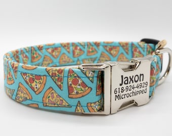 May include: A dog collar with a light blue background and a repeating pattern of pizza slices. The collar has a silver metal buckle with the name "Jaxon" and a phone number. The collar is designed for pets.