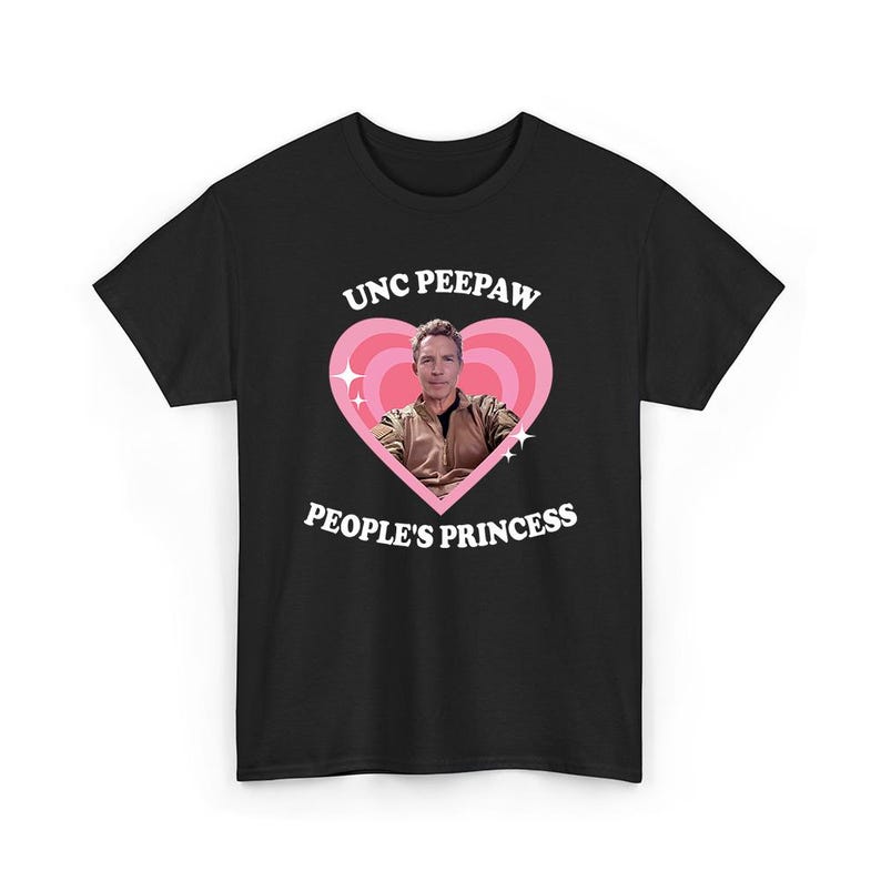 K&ouml;nnte beinhalten: Schwarzes T-Shirt mit einem rosa Herzdesign. Der Text "UNC PEEPAW" steht &uuml;ber dem Herzen und "PEOPLE'S PRINCESS" darunter. Im Inneren des Herzens befindet sich ein Foto eines Mannes. Zwei wei&szlig;e Sternausbr&uuml;che flankieren das Herz.