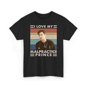 Puede incluir: Camiseta negra con un diseño retro. El texto "I LOVE MY MALPRACTICE PRINCE" está encima y debajo de una imagen de un hombre con un estetoscopio. El diseño tiene un aspecto vintage con rayas horizontales en rojo, naranja, amarillo y azul.