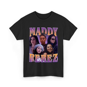Pode incluir: T-shirt preto com um gráfico de cinco mulheres e o texto "MADDY PEREZ" em um gradiente roxo e laranja. O design tem uma estética vintage. A t-shirt é feita de um material macio.