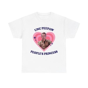 K&ouml;nnte beinhalten: Wei&szlig;es T-Shirt mit einem rosa Herzdesign. Der Text "UNC PEEPAW" steht &uuml;ber dem Herzen und "PEOPLE'S PRINCESS" darunter. Ein Foto eines Mannes befindet sich im Herzen. Das T-Shirt hat einen Rundhalsausschnitt.