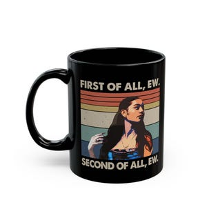Può includere: Tazza in ceramica nera con la scritta "FIRST OF ALL, EW. SECOND OF ALL, EW." e una grafica di una donna con lunghi capelli scuri. Il design ha uno stile retrò con uno sfondo a strisce arancioni, gialle e blu. La tazza ha un manico nero.