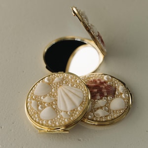 May include: A set of three ceramic mugs with a speckled, matte finish. The mugs are in shades of cream, light gray, and dark gray. Each mug has a simple, minimalist design and a rounded handle.