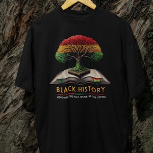May include: Black t-shirt with a graphic of a tree growing out of an open book. The tree has red, yellow, and green leaves. The text "BLACK HISTORY" is printed below the graphic, with the words "HONORING THE PAST. INSPIRING THE FUTURE" printed below that.