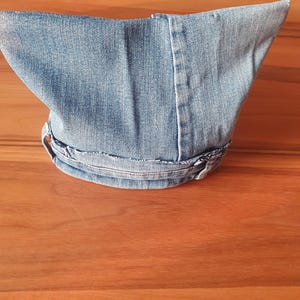 May include: A light blue denim hat with a pointed crown and a curved brim. The hat is made from a light wash denim material and features visible stitching details. The brim is secured with a denim band.