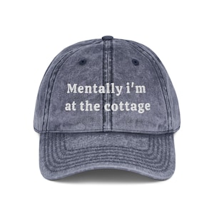 Peut inclure: Casquette de baseball bleu denim délavé avec la phrase brodée en blanc "Mentally I'm at the cottage". La casquette a une visière incurvée et une sangle réglable.