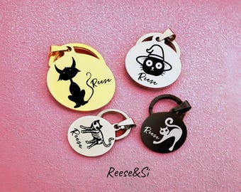 May include: Four circular metal pet tags with split rings. One gold tag features a black cat silhouette, one silver tag shows a cat in a witch hat, one silver tag displays a skeleton cat, and one black tag depicts a white cat, all engraved with Reese.