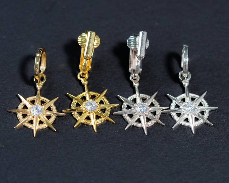 Op de afbeelding: Vier paar gouden en zilveren stervormige oorbellen met heldere strass steentjes. De oorbellen hebben een clip sluiting.